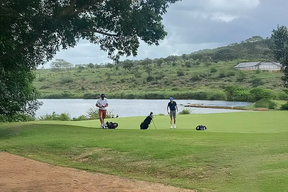 Golfers on green near lake and trees