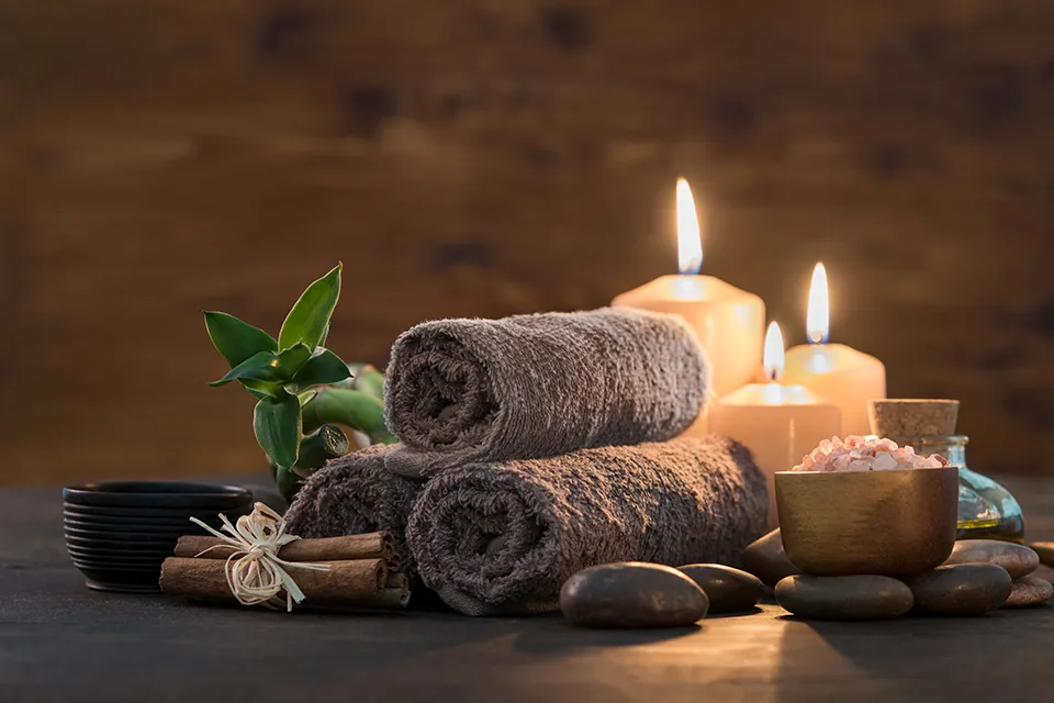 Relaxing spa setting with candles and towels.